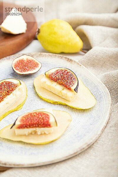 Sommerliche Vorspeise mit Birne  Hüttenkäse  Feigen und Honig auf einem weißen Holzhintergrund und Leinenstoff. Seitenansicht  Nahaufnahme  selektiver Fokus