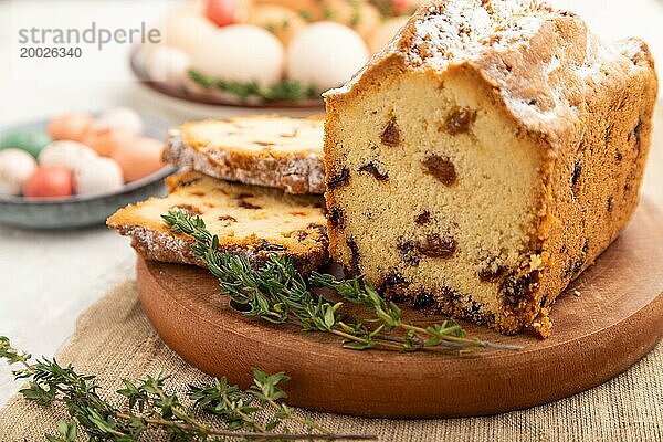 Hausgemachter Osterkuchen mit Rosinen und Eiern auf einem Teller auf einem grauen Betonhintergrund und Leinenstoff. Seitenansicht  selektiver Fokus  Nahaufnahme