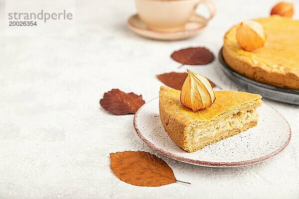 Herbst Zwiebelkuchen mit Blättern und Tasse Kaffee auf grauem Beton Hintergrund dekoriert. Seitenansicht  Nahaufnahme  selektiver Fokus