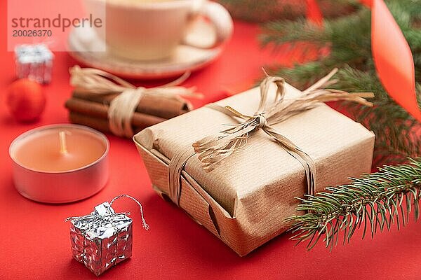 Weihnachten oder Neujahr Zusammensetzung. Dekorationen  Box  Zimt  Tanne und Fichte Zweige  Tasse Kaffee  auf einem roten Papier Hintergrund. Seitenansicht  cclose up  selektiver Fokus