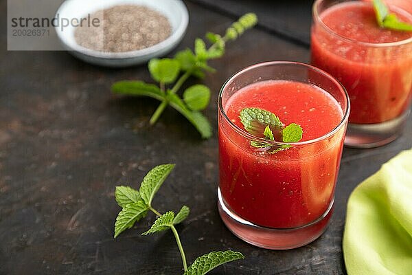 Wassermelonensaft mit Chiasamen und Minze im Glas auf einem schwarzen Betonhintergrund mit grünem Textil. Gesundes Getränk Konzept. Seitenansicht  Nahaufnahme  selektiver Fokus