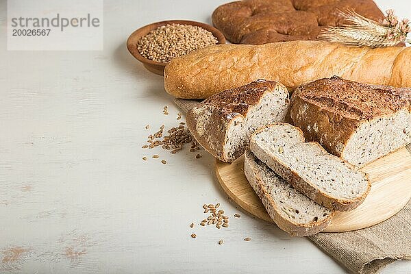 Aufgeschnittenes Brot mit verschiedenen Sorten frisch gebackenen Brotes auf weißem Holzhintergrund. Seitenansicht  Nahaufnahme  Kopierraum