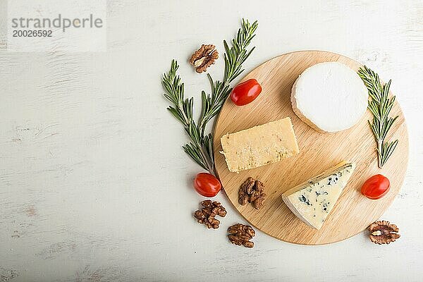 Blauschimmelkäse und verschiedene Käsesorten mit Rosmarin und Tomaten auf einem Holzbrett auf einem weißen Holzhintergrund. Draufsicht  Kopierraum  Flat Lay