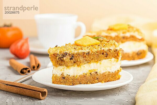 Hausgemachter Kuchen mit Kaki und Kürbis und einer Tasse Kaffee auf einem grauen Betonhintergrund mit gelbem Textil. Seitenansicht  Nahaufnahme  selektiver Fokus