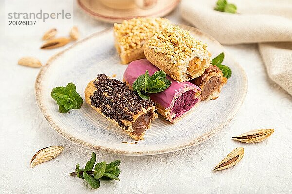 Set von Eclair  traditionelles französisches Dessert und Tasse Kaffee auf grauem Betonhintergrund und Leinenstoff. Seitenansicht  Nahaufnahme  selektiver Fokus  Stillleben. Frühstück  Morgen  Konzept