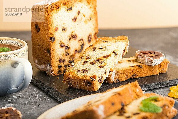 Hausgemachter Kuchen mit Rosinen  getrockneten Kaki und einer Tasse heißer Schokolade auf einem schwarzen Betonhintergrund. Seitenansicht  Nahaufnahme  Kopierraum  selektiver Fokus