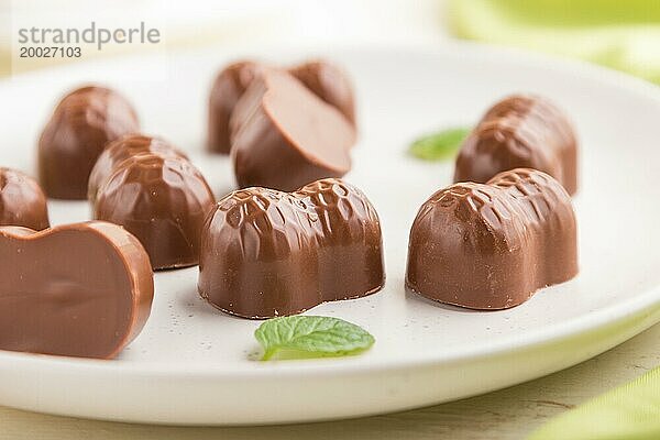 Schokoladenbonbons mit Mandeln auf einem weißen Holzhintergrund und grünem Textil. Seitenansicht  Nahaufnahme  selektiver Fokus