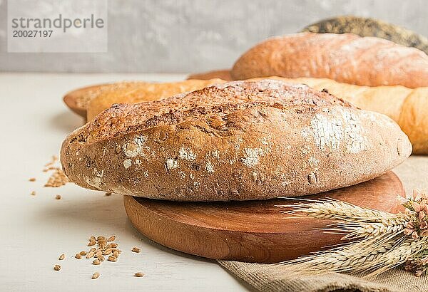 Verschiedene Arten von frisch gebackenem Brot auf einem weißen hölzernen Hintergrund. Seitenansicht  Nahaufnahme  selektiver Fokus