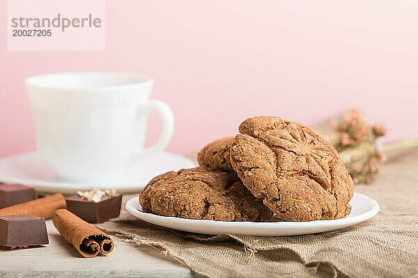 Hausgemachte Haferflockenkekse mit einer Tasse Kakao auf einem Leinenstoff und rosa Pastell Hintergrund. Seitenansicht  Nahaufnahme  selektiver Fokus