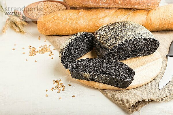 Aufgeschnittenes Schwarzbrot mit verschiedenen Arten von frisch gebackenem Brot auf weißem Holzhintergrund. Seitenansicht  Nahaufnahme  Kopierraum