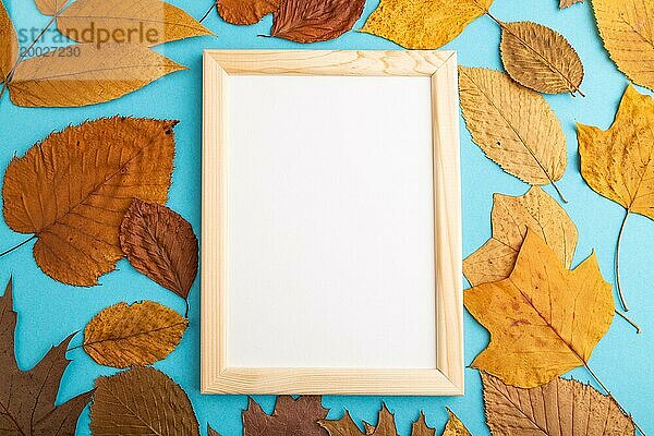 Komposition mit gelben und braunen Herbstblättern und Holzrahmen Mockup auf blauem Pastell Hintergrund. Leer  flat lay  Draufsicht  Stillleben  copy space