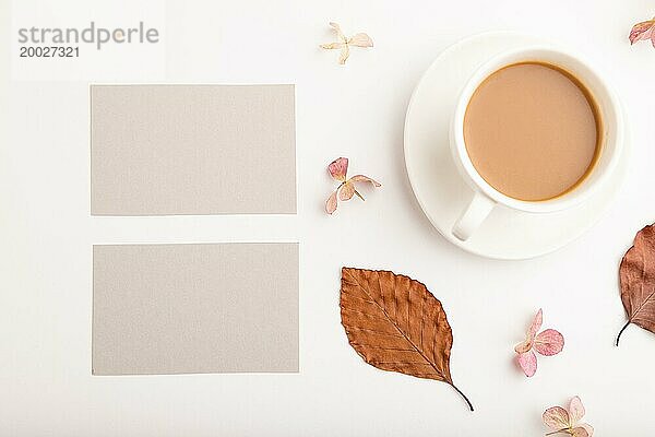 Komposition mit grauem Papier Visitenkarte  braune Buche Herbstblätter  Hortensienblüten und Tasse Kaffee. Mockup auf weißem Hintergrund. Blank  flach legen  Draufsicht  Stillleben  Kopie Raum