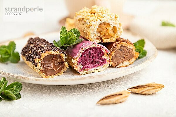 Set von Eclair  traditionelles französisches Dessert und Tasse Kaffee auf grauem Betonhintergrund und Leinenstoff. Seitenansicht  Nahaufnahme  selektiver Fokus  Stillleben. Frühstück  Morgen  Konzept