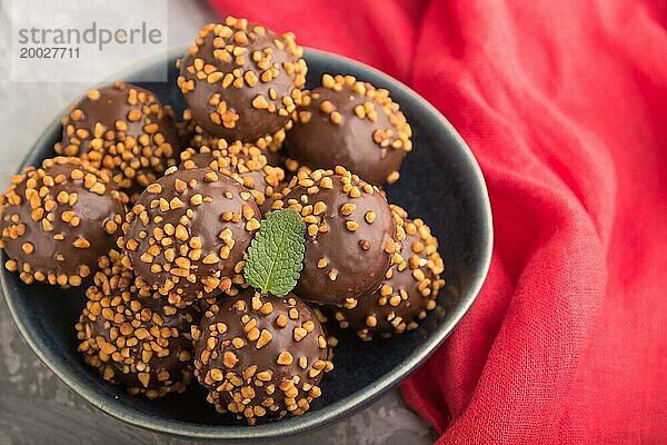 Karamellbonbons mit Mandeln und einer Tasse Kaffee auf einem grauen Betonhintergrund und rotem Stoff. Seitenansicht  Nahaufnahme  selektiver Fokus