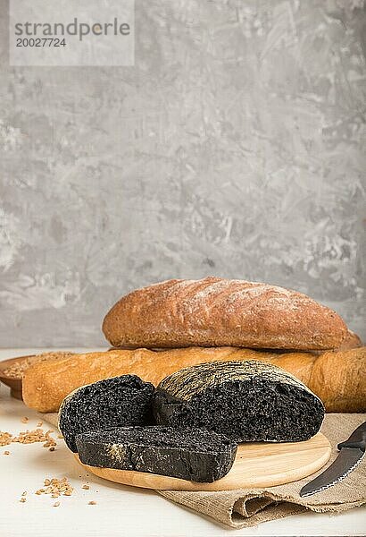 Aufgeschnittenes Schwarzbrot mit verschiedenen Arten von frisch gebackenem Brot auf grauem Betonhintergrund. Seitenansicht  Nahaufnahme  selektiver Fokus