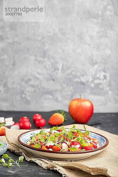 Vegetarischer Obst und Gemüsesalat aus Erdbeeren  Kiwi  Tomaten  Mikrogrünsprossen auf schwarzem und grauem Hintergrund und Leinentuch. Seitenansicht  selektiver Fokus  Kopierraum