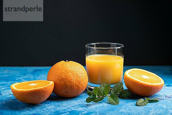 Glas Orangensaft mit Minze auf einem schwarzen und blaün Hintergrund. Hartes Licht  Kontrast. Seitenansicht  Kopierraum