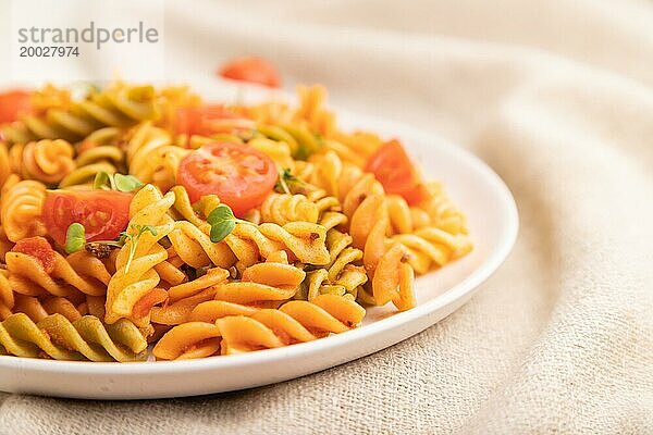 Tortiglioni Grießnudeln mit Tomate und Mikrogrünsprossen auf weißem Holzhintergrund und Leinentextil. Seitenansicht  Nahaufnahme  selektiver Fokus