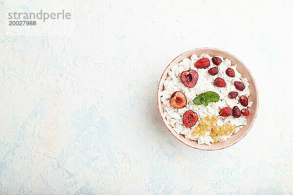 Reisflockenbrei mit Milch und Erdbeere in Keramikschale auf weißem Betonhintergrund. Draufsicht  flat lay  copy space