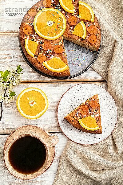 Orangenkuchen und eine Tasse Kaffee auf einem weißen Holzhintergrund und Leinentextil. Draufsicht  flach gelegt  Nahaufnahme