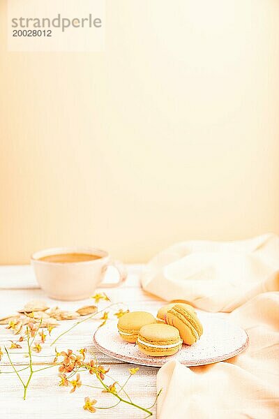 Orangenmakronen oder Makronen Kuchen mit einer Tasse Aprikosensaft auf einem weißen hölzernen Hintergrund und orangefarbenen Leinenstoff. Seitenansicht  Kopierraum  selektiver Fokus