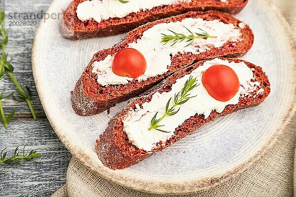 Rote Bete Sandwiches mit Frischkäse und Tomaten auf grauem Holzhintergrund und Leinenstoff. Draufsicht  Nahaufnahme  selektiver Fokus