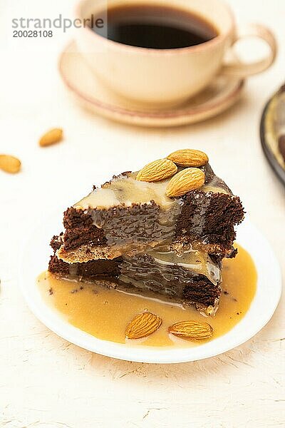 Stücke von Schokoladen Brownie Kuchen mit Karamellcreme und Mandeln auf einem weißen Betonhintergrund. Seitenansicht  Nahaufnahme  selektiver Fokus