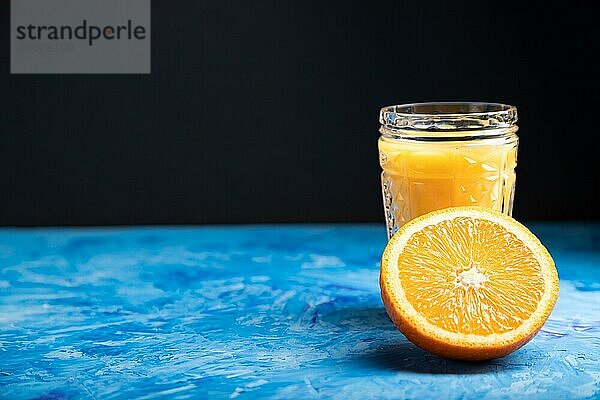 Glas Orangensaft auf einem schwarzen und blaün Hintergrund. Hartes Licht  Kontrast. Seitenansicht  Kopierraum