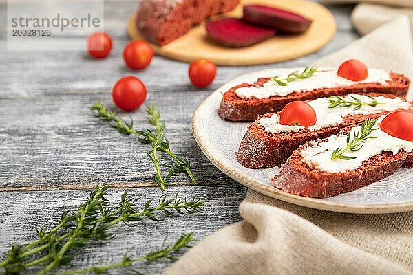 Rote Bete Sandwiches mit Frischkäse und Tomaten auf grauem Holzhintergrund und Leinenstoff. Seitenansicht  Nahaufnahme  selektiver Fokus