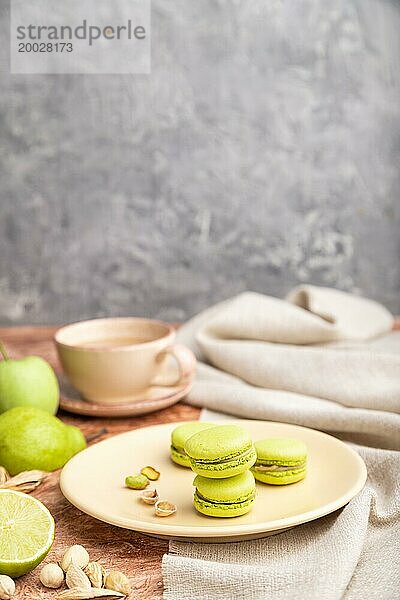 Grüne Macarons oder Makronen Kuchen mit Tasse Kaffee auf einem braunen und grauen Beton Hintergrund und Leinen Textil. Seitenansicht  Kopierraum  selektiver Fokus