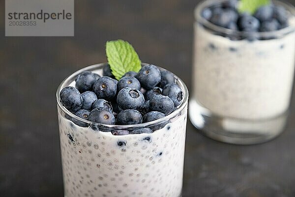 Joghurt mit Heidelbeeren und Chia im Glas auf schwarzem Betonhintergrund. Seitenansicht  Nahaufnahme