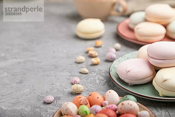 Farbiger Zephir oder Marshmallow mit Kaffeetasse und Dragees auf grauem Betonhintergrund und Leinenstoff. Seitenansicht  Nahaufnahme  selektiver Fokus  Kopierraum