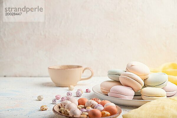 Farbiger Zephir oder Marshmallow mit Kaffeetasse und Dragees auf weißem Betonhintergrund und gelbem Textil. Seitenansicht  Kopierraum  selektiver Fokus