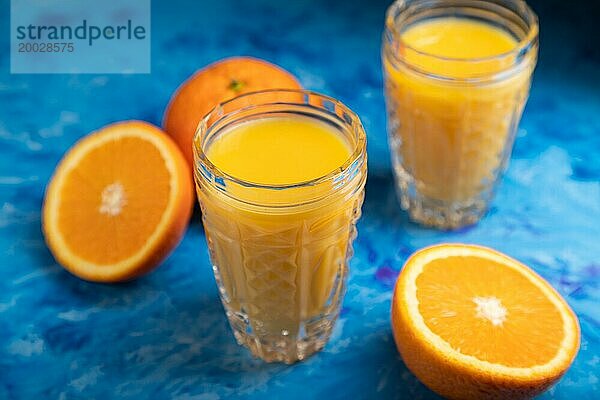 Glas Orangensaft auf einem schwarzen und blaün Hintergrund. Hartes Licht  Kontrast. Seitenansicht  Nahaufnahme