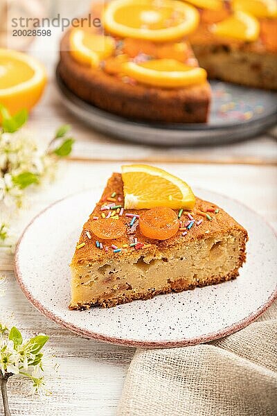 Orangenkuchen und eine Tasse Kaffee auf einem weißen Holzhintergrund und Leinentextil. Seitenansicht  Nahaufnahme  selektiver Fokus