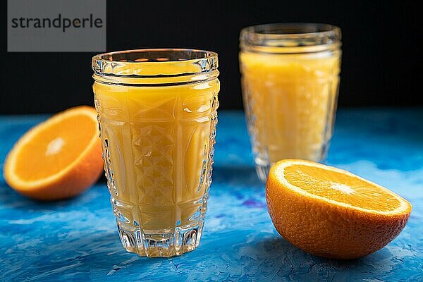 Glas Orangensaft auf einem schwarzen und blaün Hintergrund. Hartes Licht  Kontrast. Seitenansicht  Nahaufnahme