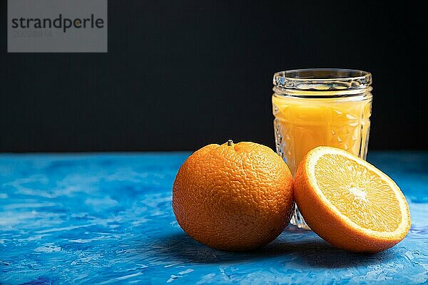 Glas Orangensaft auf einem schwarzen und blaün Hintergrund. Hartes Licht  Kontrast. Seitenansicht  Kopierraum