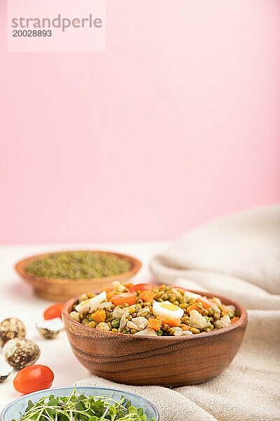 Mungobohnenbrei mit Wachteleiern  Tomaten und mikrogrünen Sprossen auf weißem und rosa Hintergrund und Leinentuch. Seitenansicht  Kopierraum  selektiver Fokus