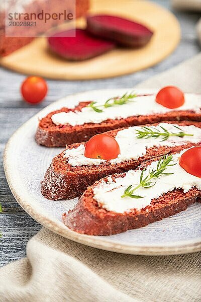 Rote Bete Sandwiches mit Frischkäse und Tomaten auf grauem Holzhintergrund und Leinenstoff. Seitenansicht  Nahaufnahme  selektiver Fokus