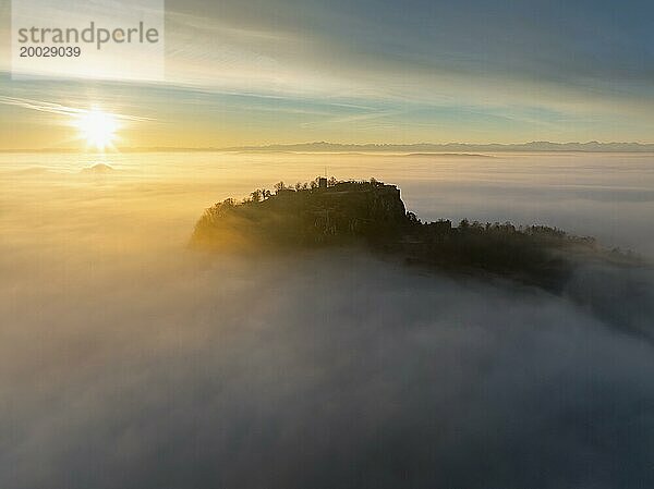 Luftbild vom Hegauvulkan Hohentwiel mit der oberen Festungsruine als Silhouette bei Sonnenaufgang  die bei einer Inversionswetterlage aus dem Nebel herausragt  Landkreis Konstanz  Baden-Württemberg  Deutschland  Europa