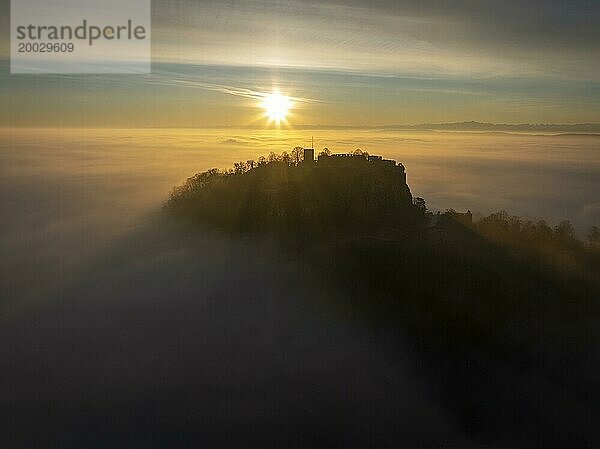 Luftbild vom Hegauvulkan Hohentwiel mit der oberen Festungsruine als Silhouette bei Sonnenaufgang  die bei einer Inversionswetterlage aus dem Nebel herausragt  Landkreis Konstanz  Baden-Württemberg  Deutschland  Europa