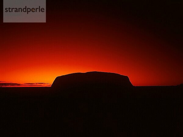 Silhouette Umriss von Ayers Rock oder Uluru in rot Sonnenaufgang oder Sonnenuntergang  Abenddämmerung oder Morgendämmerung  roten Himmel  Northern Territory  Australien  Ozeanien