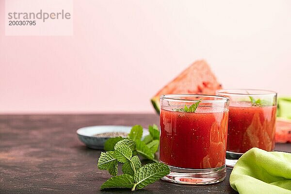 Wassermelonensaft mit Chiasamen und Minze in einem Glas auf einem schwarzen und rosa Hintergrund mit grünem Stoff. Gesundes Getränk Konzept. Seitenansicht  Nahaufnahme  selektiver Fokus  Kopierraum