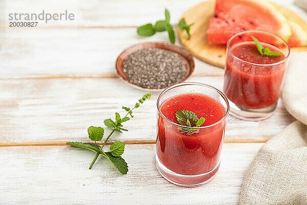 Wassermelonensaft mit Chiasamen und Minze in einem Glas auf einem weißen Holzhintergrund mit Leinenstoff. Gesundes Getränk Konzept. Seitenansicht  Nahaufnahme  selektiver Fokus  Kopierraum