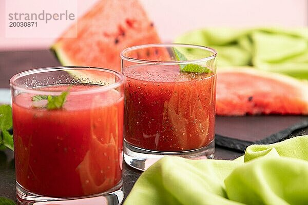 Wassermelonensaft mit Chiasamen und Minze im Glas auf einem schwarzen Betonhintergrund mit grünem Textil. Gesundes Getränk Konzept. Seitenansicht  Nahaufnahme  selektiver Fokus