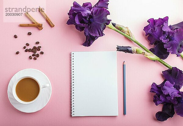 Lila Irisblüten und eine Tasse Kaffee mit Notizbuch auf pastellrosa Hintergrund. Morninig  Frühling  Mode Zusammensetzung. Flachlage  Draufsicht  Kopierraum