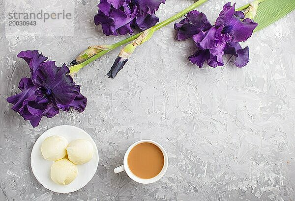 Lila Irisblüten und eine Tasse Kaffee mit Marshmallow auf einem grauen Betonhintergrund. Morninig  Frühling  Mode Zusammensetzung. Flachlage  Draufsicht  Kopierraum