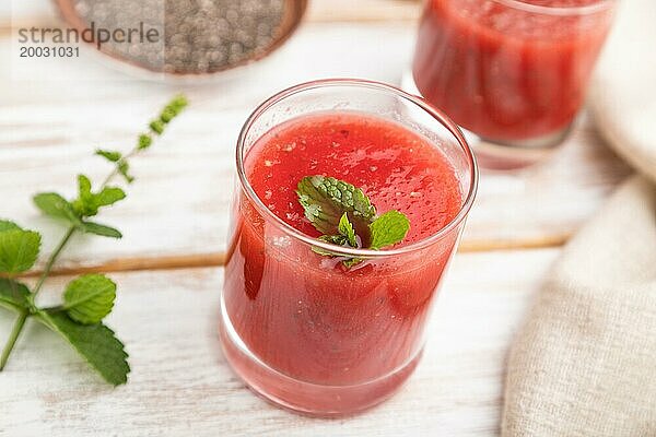 Wassermelonensaft mit Chiasamen und Minze in einem Glas auf einem weißen Holzhintergrund mit Leinenstoff. Gesundes Getränk Konzept. Seitenansicht  Nahaufnahme  selektiver Fokus