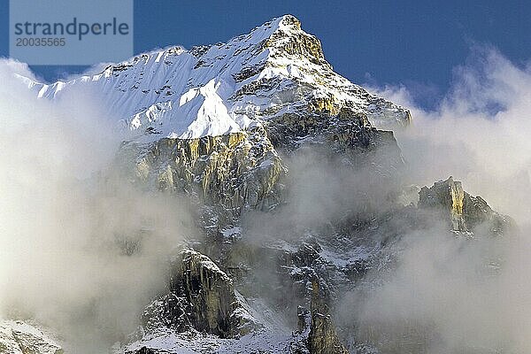 Nebel und Wolken sammeln sich am Nachmittag um die dramatischen Felsen und den Gipfel eines unbenannten Gipfels in der Kangchenjunga Region im Osten Nepals