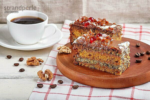 Ein Stück Kuchen mit Karamellcreme und Mohn auf einem hölzernen Küchenbrett und eine Tasse Kaffee  Nahaufnahme  weißer Hintergrund